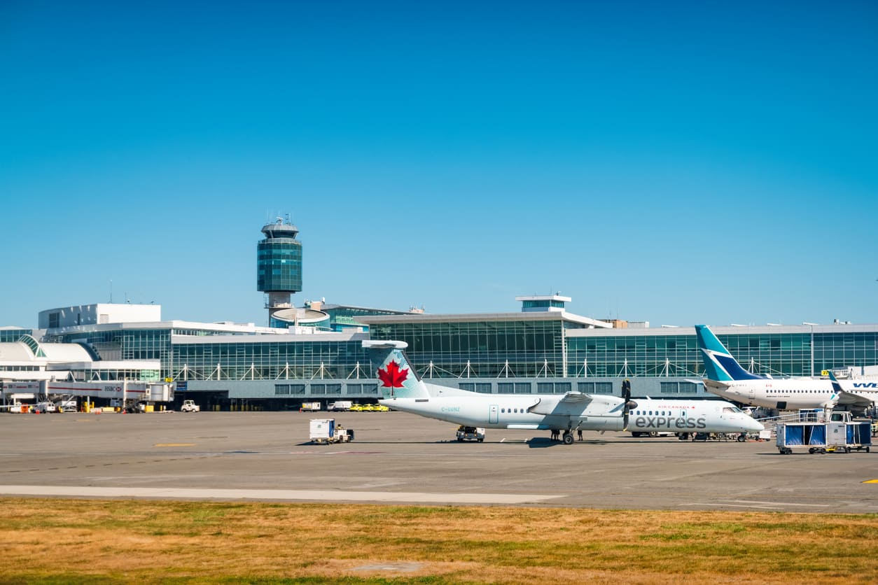 Vancouver International Airport showcases its sleek terminal, control tower, and aircraft from Air Canada and WestJet stationed on the tarmac.