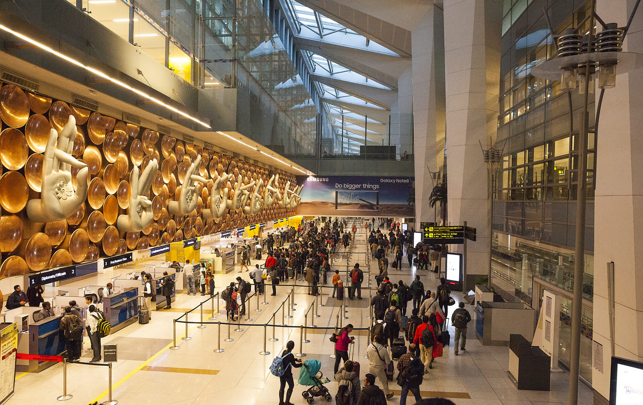 The vibrant interior of Indira Gandhi International Airport features iconic hand gesture art and a busy, modern terminal.