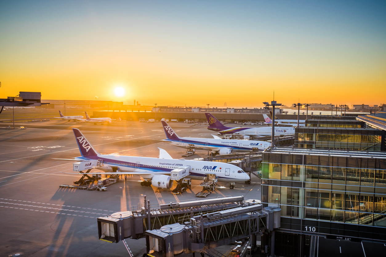 A picturesque sunrise at Haneda Airport with ANA aircraft and modern terminals, showcasing its global aviation hub status.