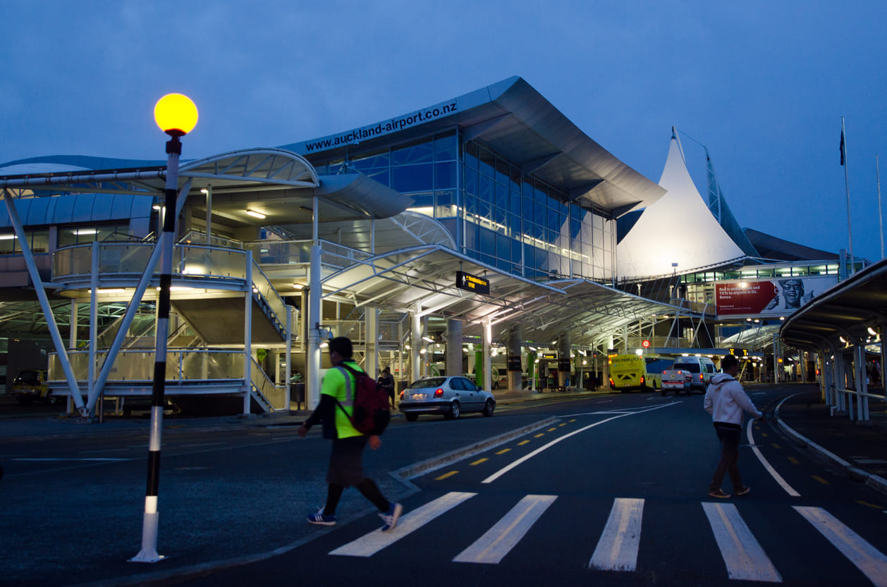 Auckland International Airport's modern exterior glows in the evening light, highlighting its sleek design and bustling atmosphere.