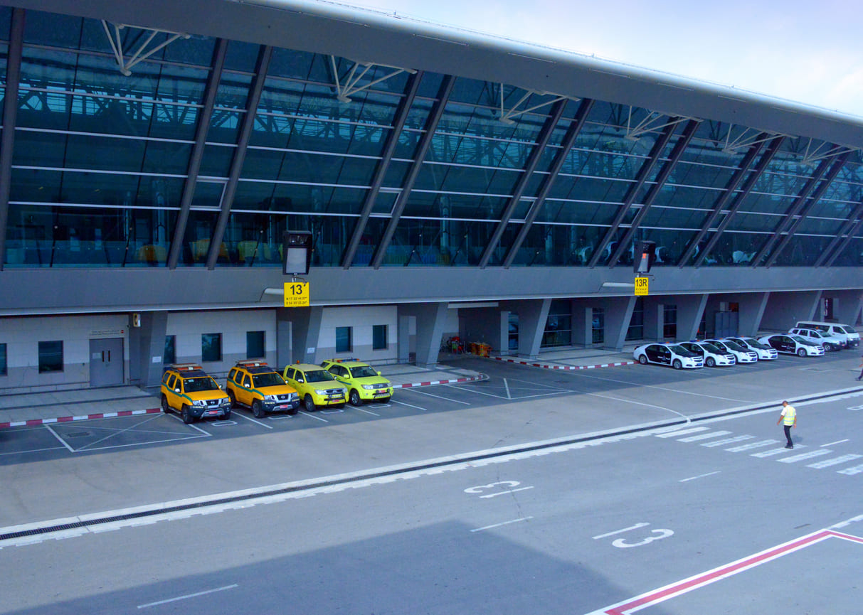 Salalah International Airport's sleek glass facade and organized service vehicle area highlight its modern infrastructure.