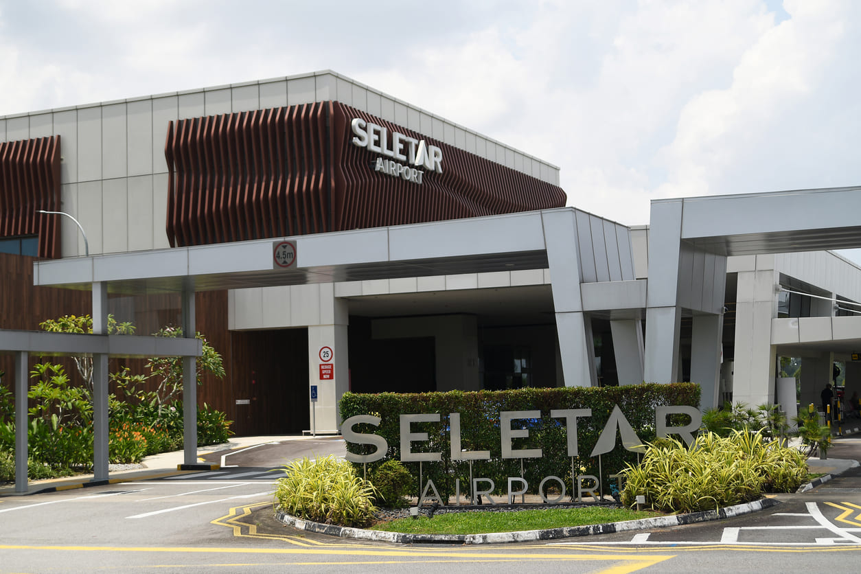 The entrance of Seletar Airport features modern architecture, clean lines, and lush greenery, reflecting its role as a premier aviation hub.