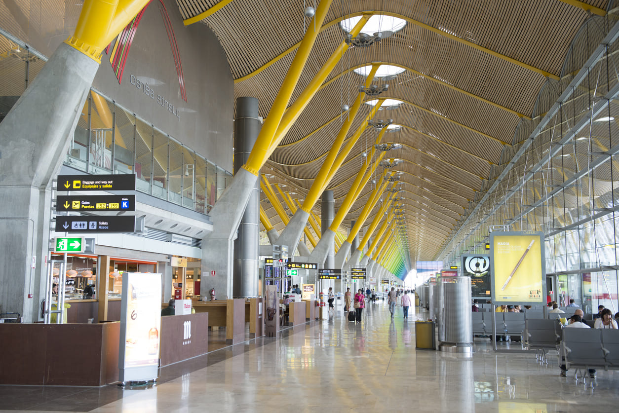 The sleek interior of Madrid-Barajas Airport's Terminal 4 showcases its iconic yellow arches, spacious layout, and abundant natural light.