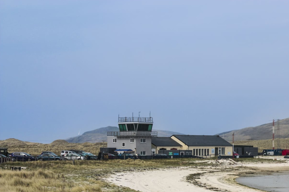 Barra Airport's control tower and terminal are situated near its iconic beach runway, surrounded by scenic island landscapes.