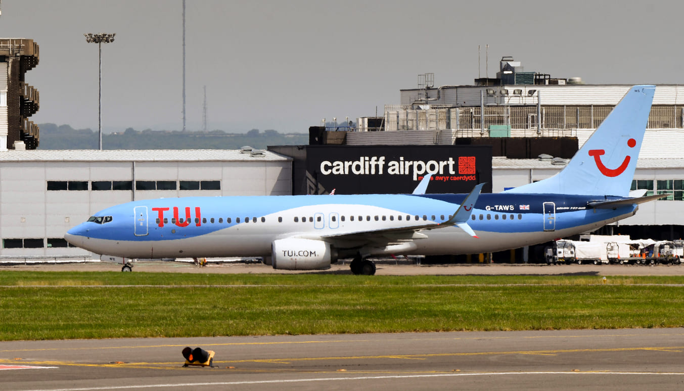 A TUI aircraft on the runway at Cardiff Airport, with the terminal in the background.