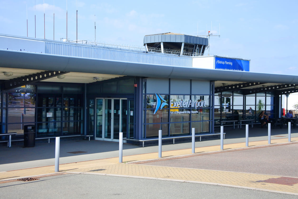 The entrance of Exeter Airport, featuring a sleek design and its control tower in the background.