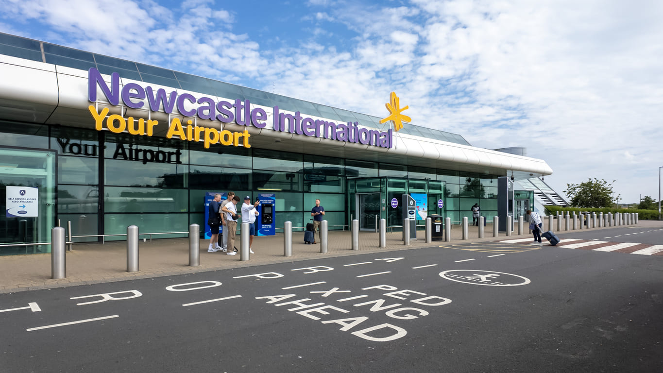 The entrance of Newcastle International Airport features modern architecture with clear signage, welcoming travelers to the region.