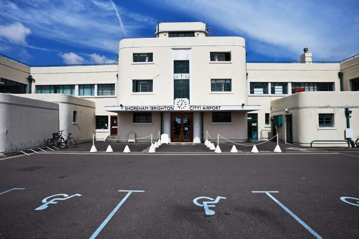 Shoreham Airport's historic Art Deco terminal building, showcasing its timeless architectural design under a bright blue sky.