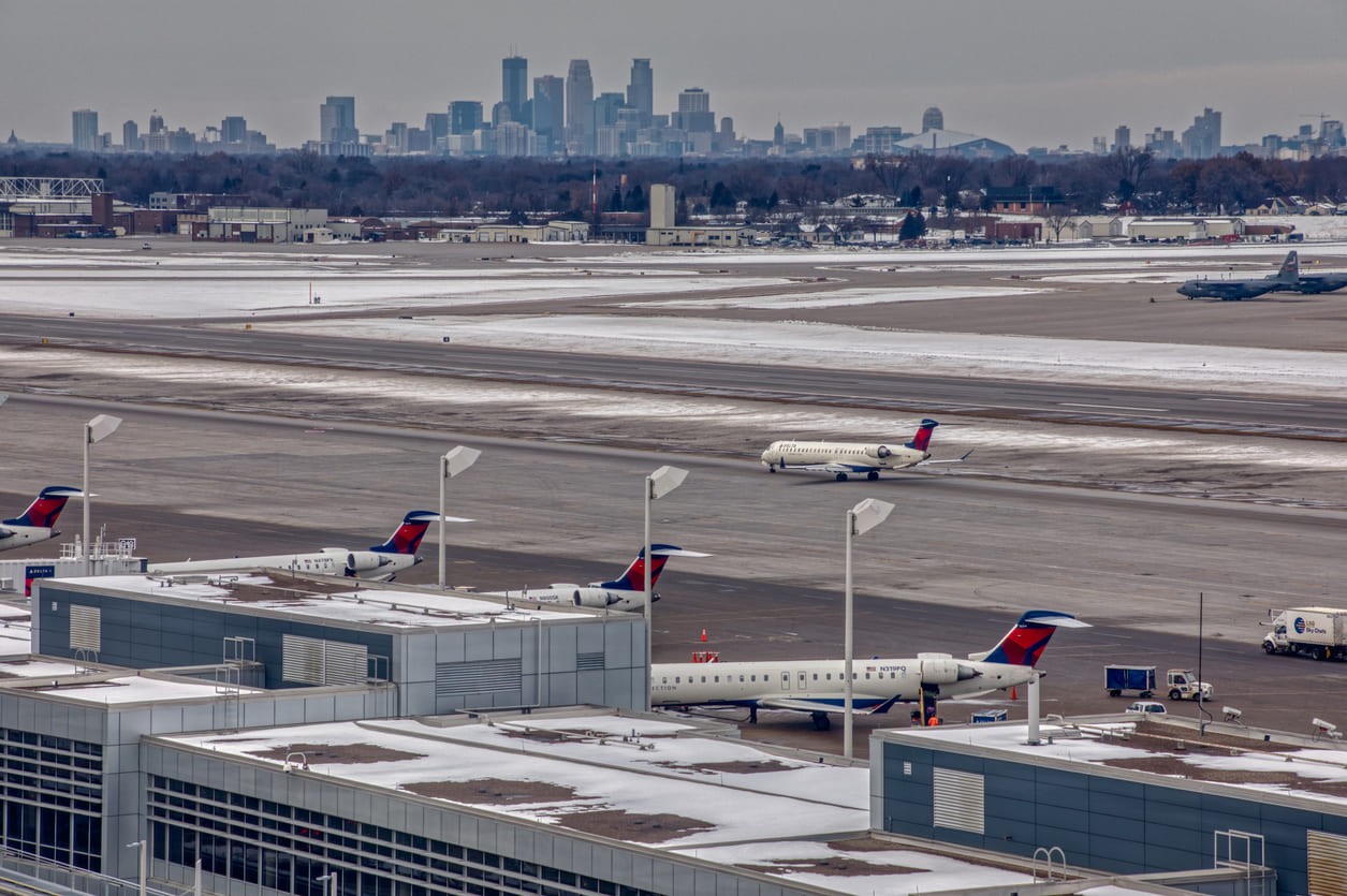 Minneapolis–Saint Paul International Airport showcases its bustling tarmac with Delta jets, set against the snowy backdrop of the Twin Cities skyline.