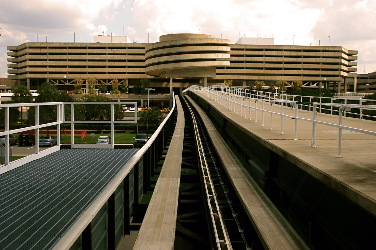 An elevated tramway at Tampa International Airport leads to the distinctive circular parking structure and main terminal.