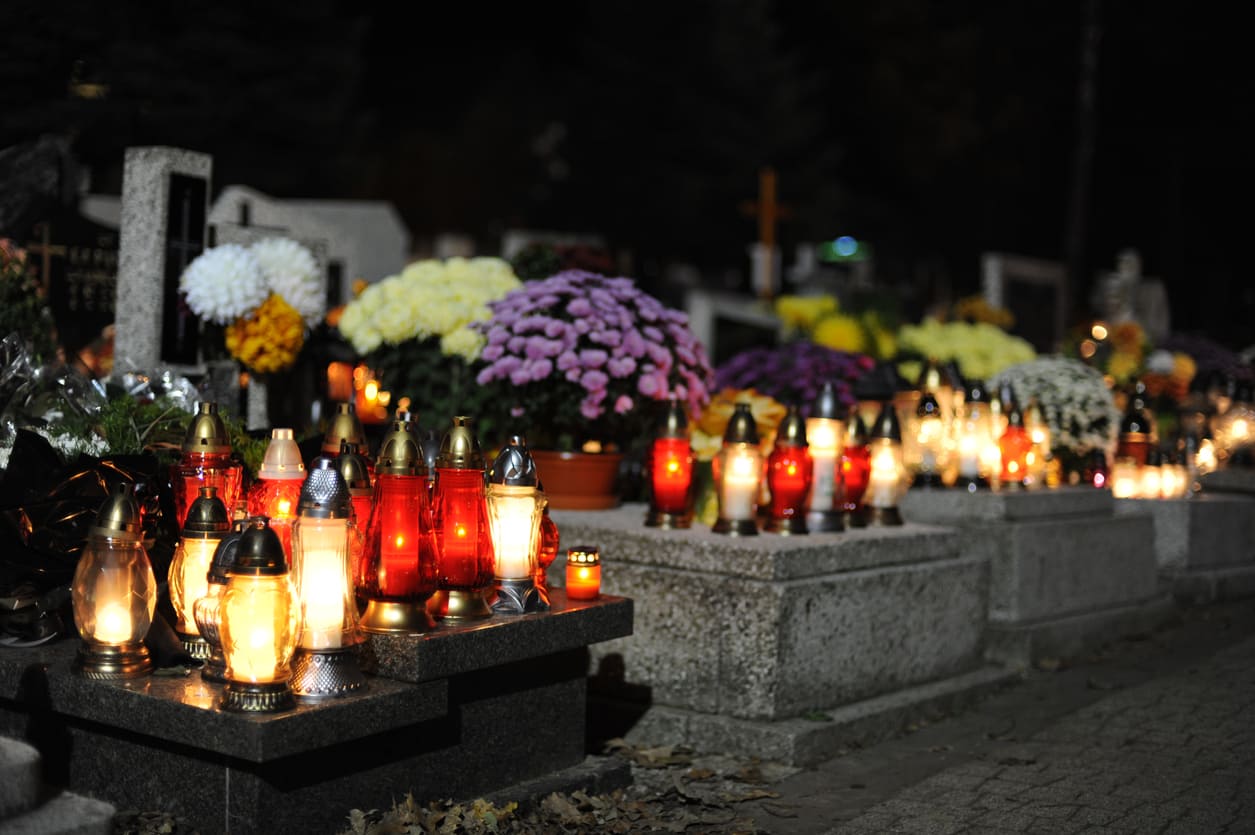 Graves beautifully adorned with glowing candles and vibrant flowers, symbolizing remembrance and respect.