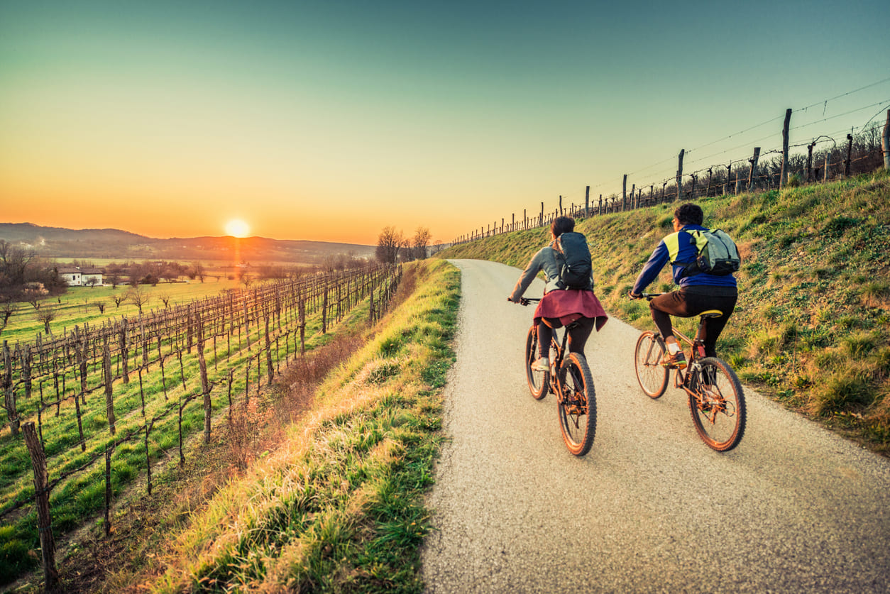 Two cyclists riding along a picturesque path at sunset, highlighting the joy of outdoor exploration and sustainable travel.