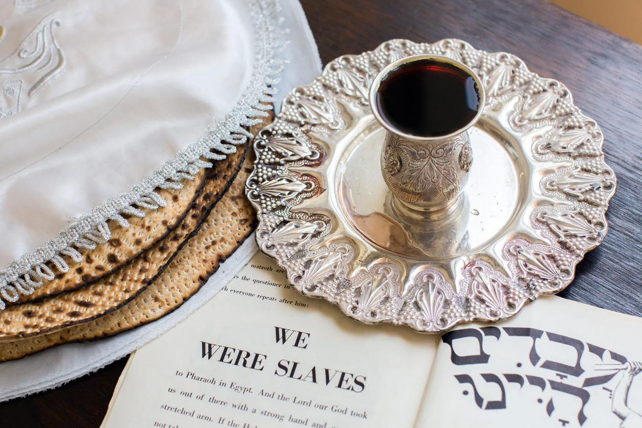 Traditional Passover elements, including matzah, a decorative wine cup, and the Haggadah.