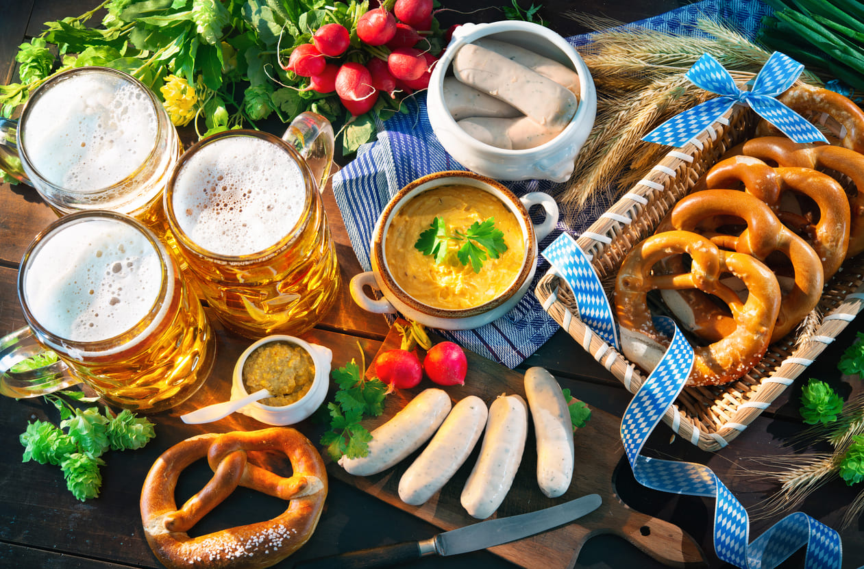 A festive Bavarian spread with beer, pretzels, white sausages, and traditional delicacies, highlighting Oktoberfest's culinary traditions.