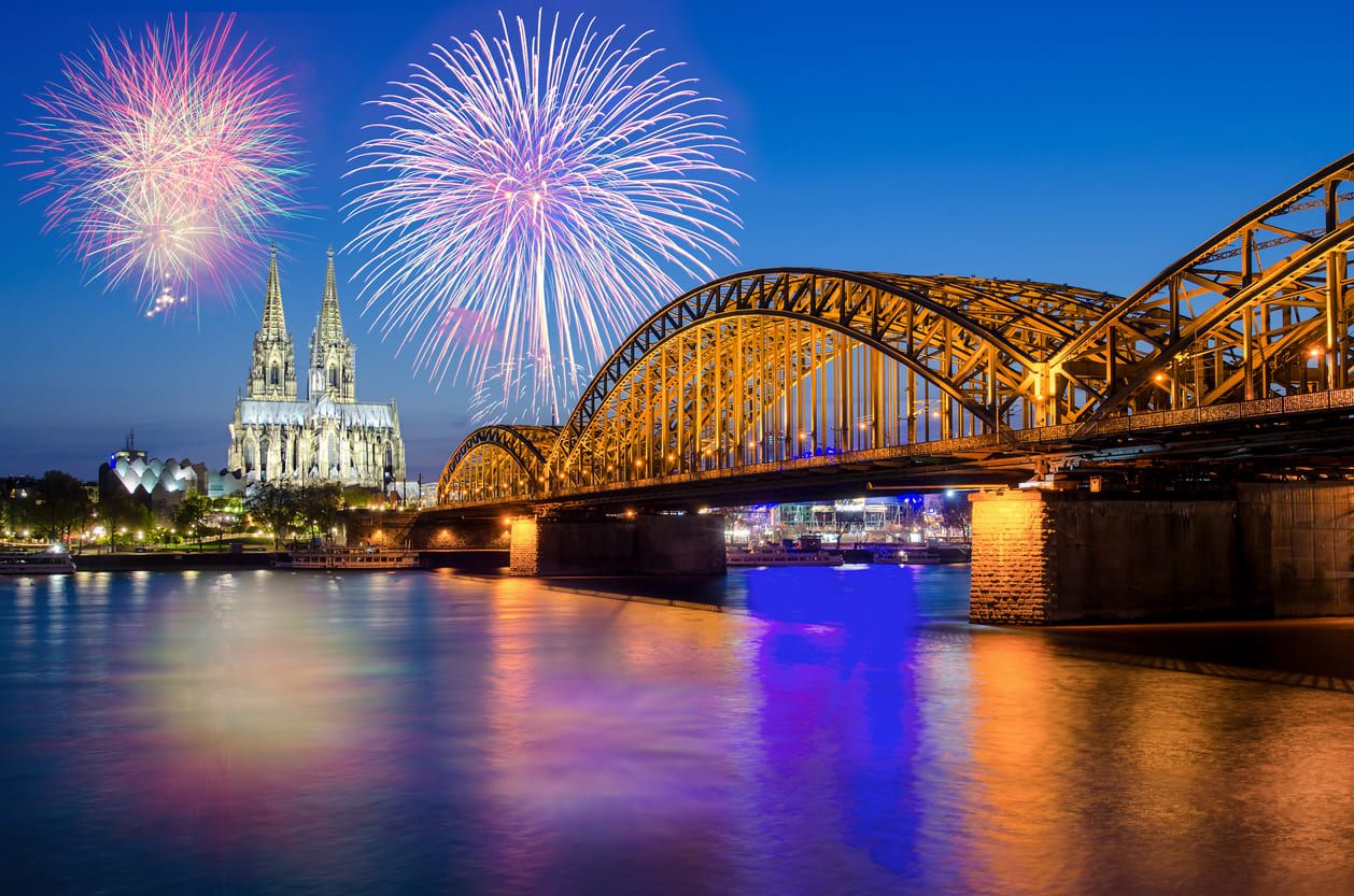 Colorful fireworks illuminate the iconic Cologne Cathedral and Hohenzollern Bridge, celebrating New Year's festivities in Germany.