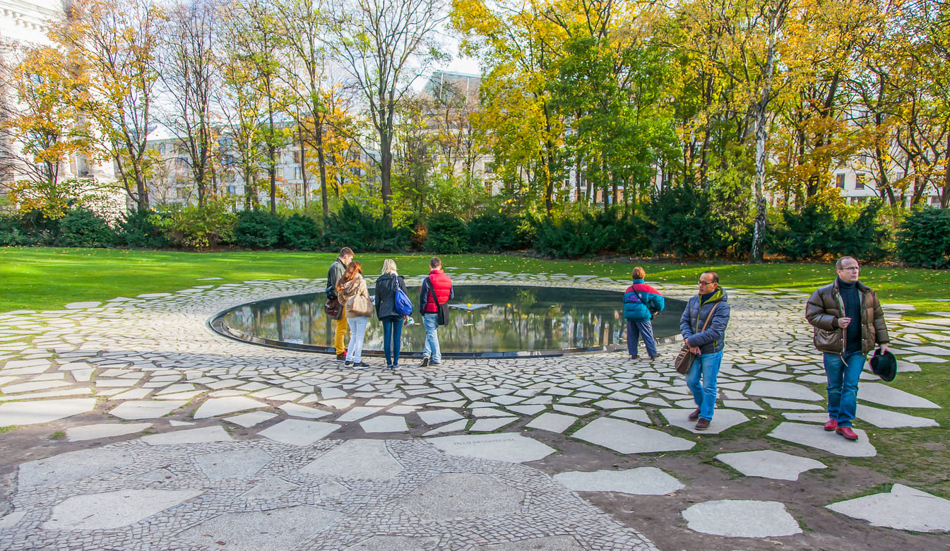 Visitors at the Memorial to the Sinti and Roma Victims of National Socialism in Berlin, a serene space for reflection and remembrance.