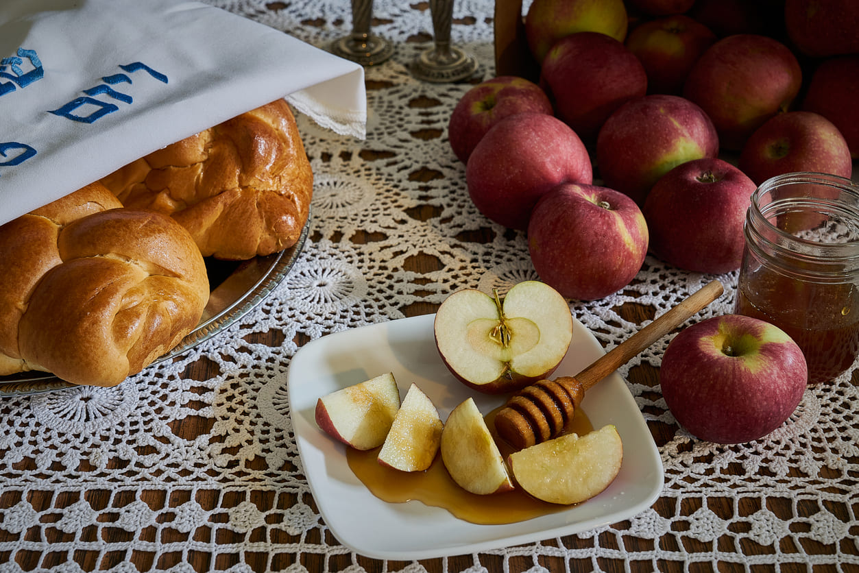 Traditional Rosh Hashanah foods, including apples, honey, and challah, symbolizing sweetness and renewal for the Jewish New Year.