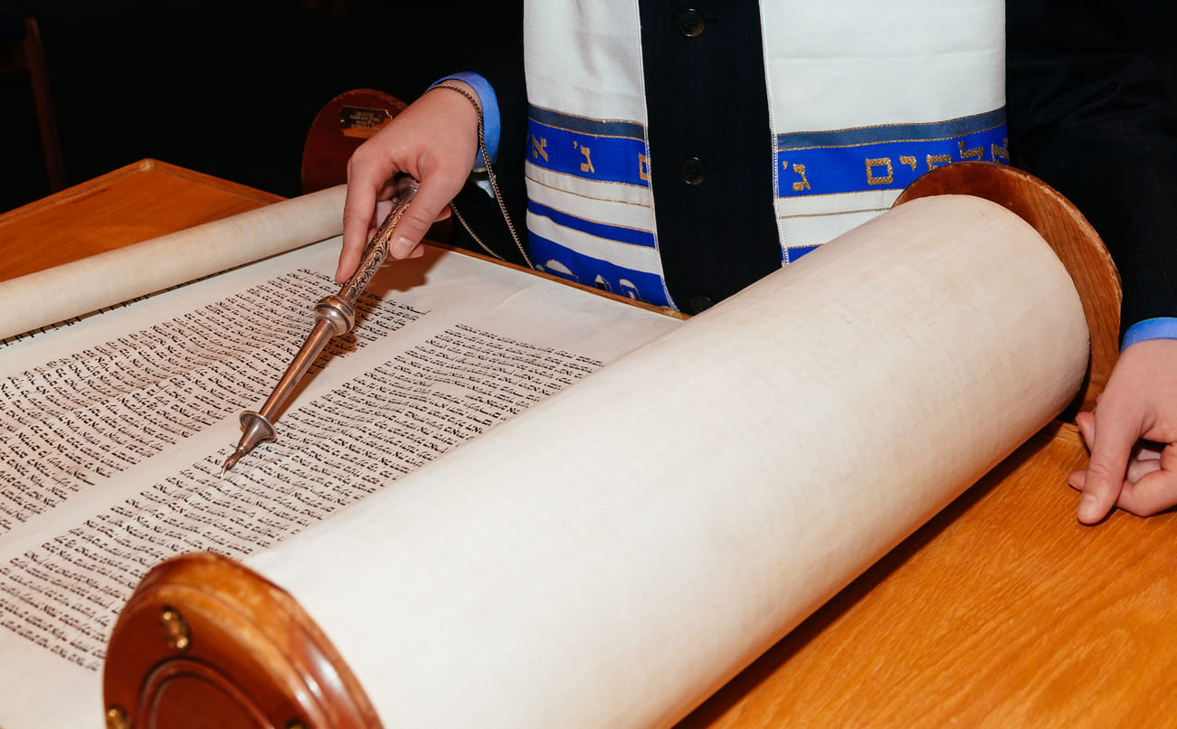 A Torah scroll being read with a yad pointer, symbolizing the importance of the Torah in Jewish traditions.