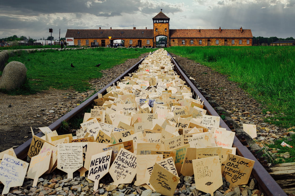 Train tracks leading to Auschwitz-Birkenau, filled with handwritten messages of remembrance and tribute left by visitors.