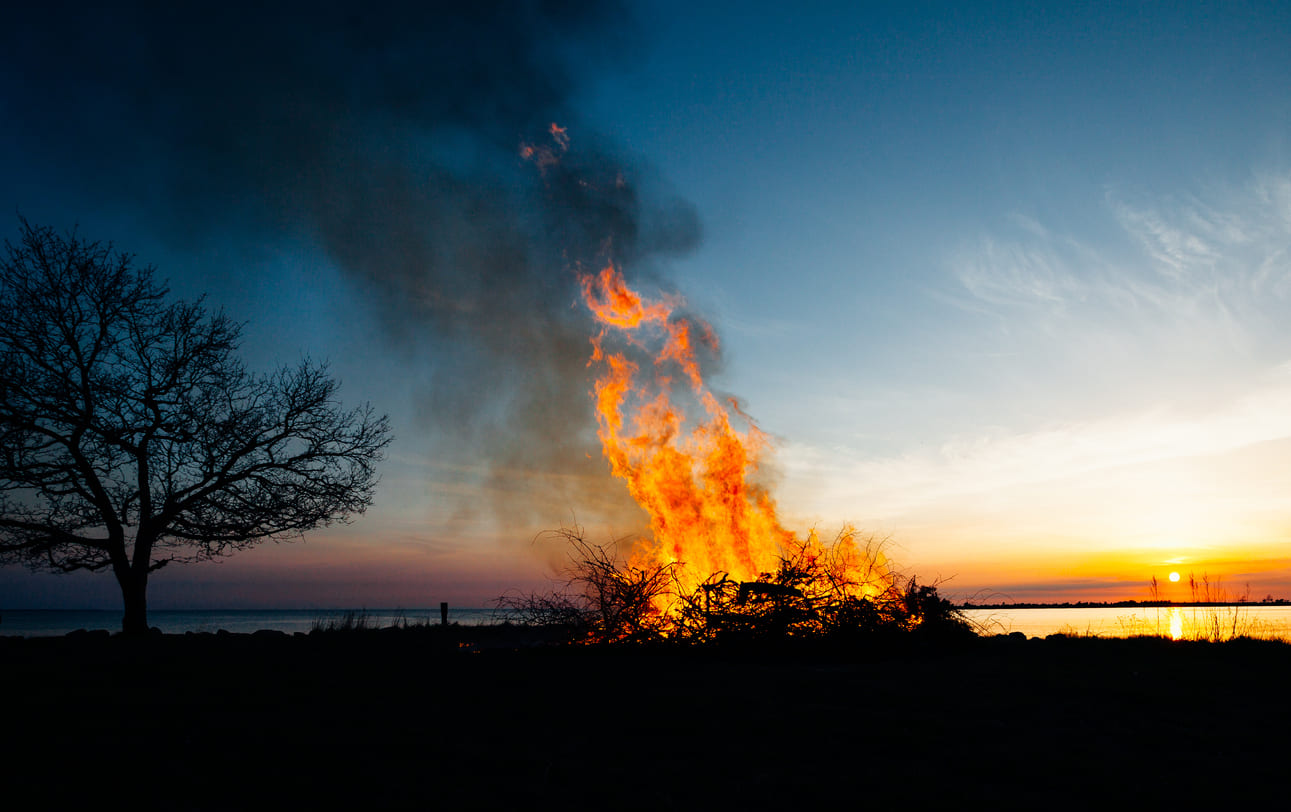 A large bonfire burning against the backdrop of a serene sunset, capturing the essence of Walpurgis Night celebrations.