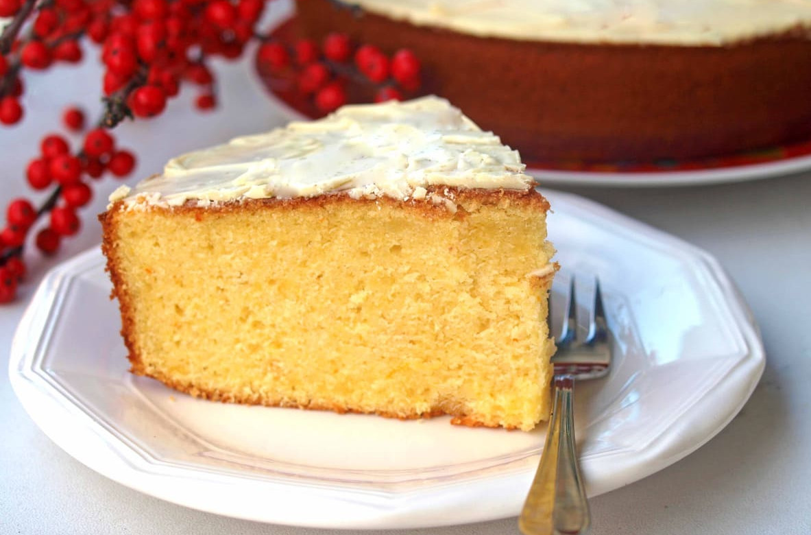 A thick, golden slice of Vasilopita topped with a light glaze sits on a plate, ready to be enjoyed as part of Greece's New Year tradition.