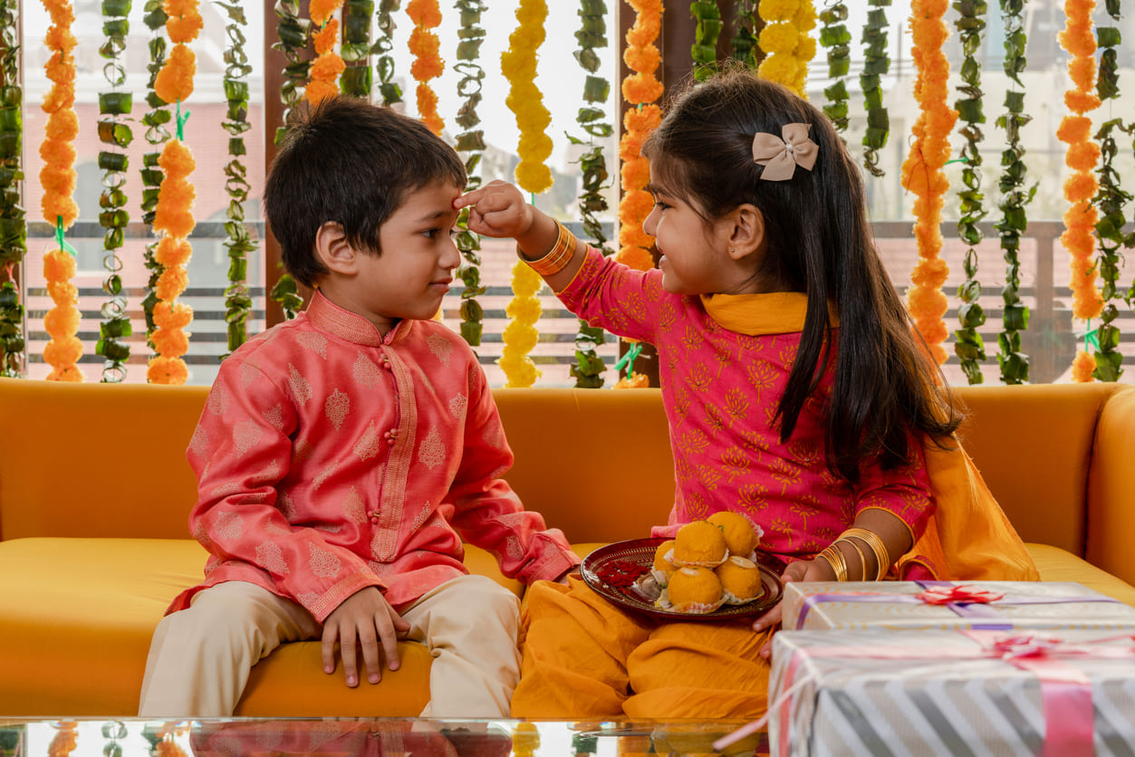 A sweet moment of a sister applying a ceremonial tikka on her brother's forehead, symbolizing love and blessings on Bhai Duj.