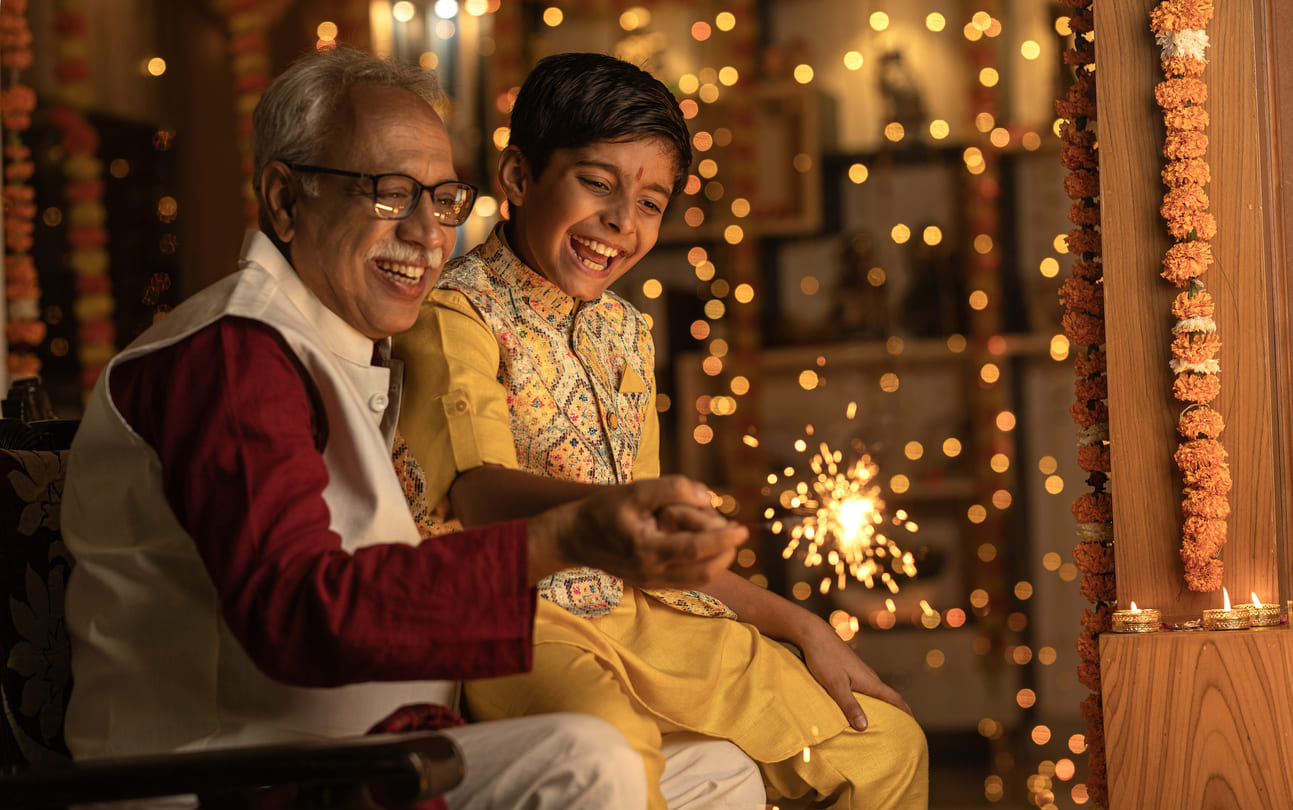 Joyful moment of a grandfather and grandson celebrating Diwali by lighting sparklers, surrounded by warm festive decorations.