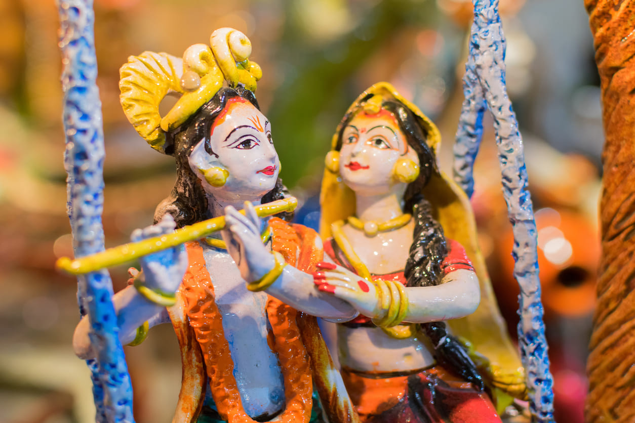 Colorful idols of Lord Krishna and Radha on a swing, symbolizing joy and divine love during Dolyatra celebrations.