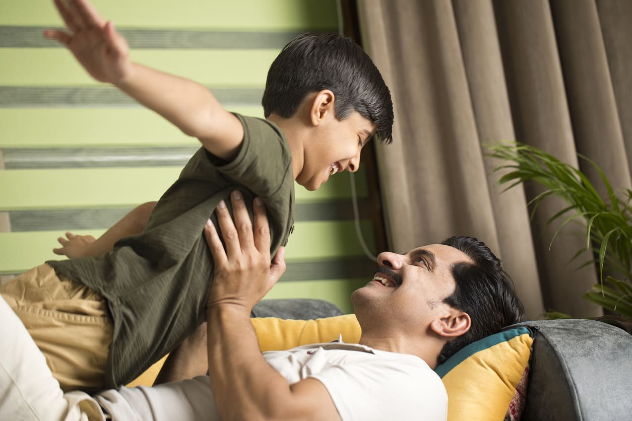 A father and son share a playful and loving moment, symbolizing their strong bond and joy.