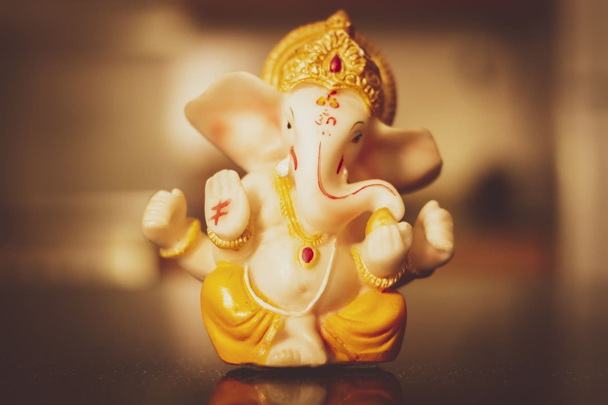 Serene idol of Lord Ganesha adorned in yellow and gold, symbolizing divine wisdom and prosperity.