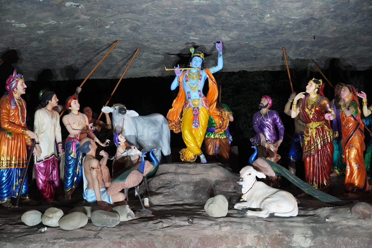 Lord Krishna lifting the Govardhan Hill to protect villagers and animals, a key moment celebrated during Govardhan Puja.