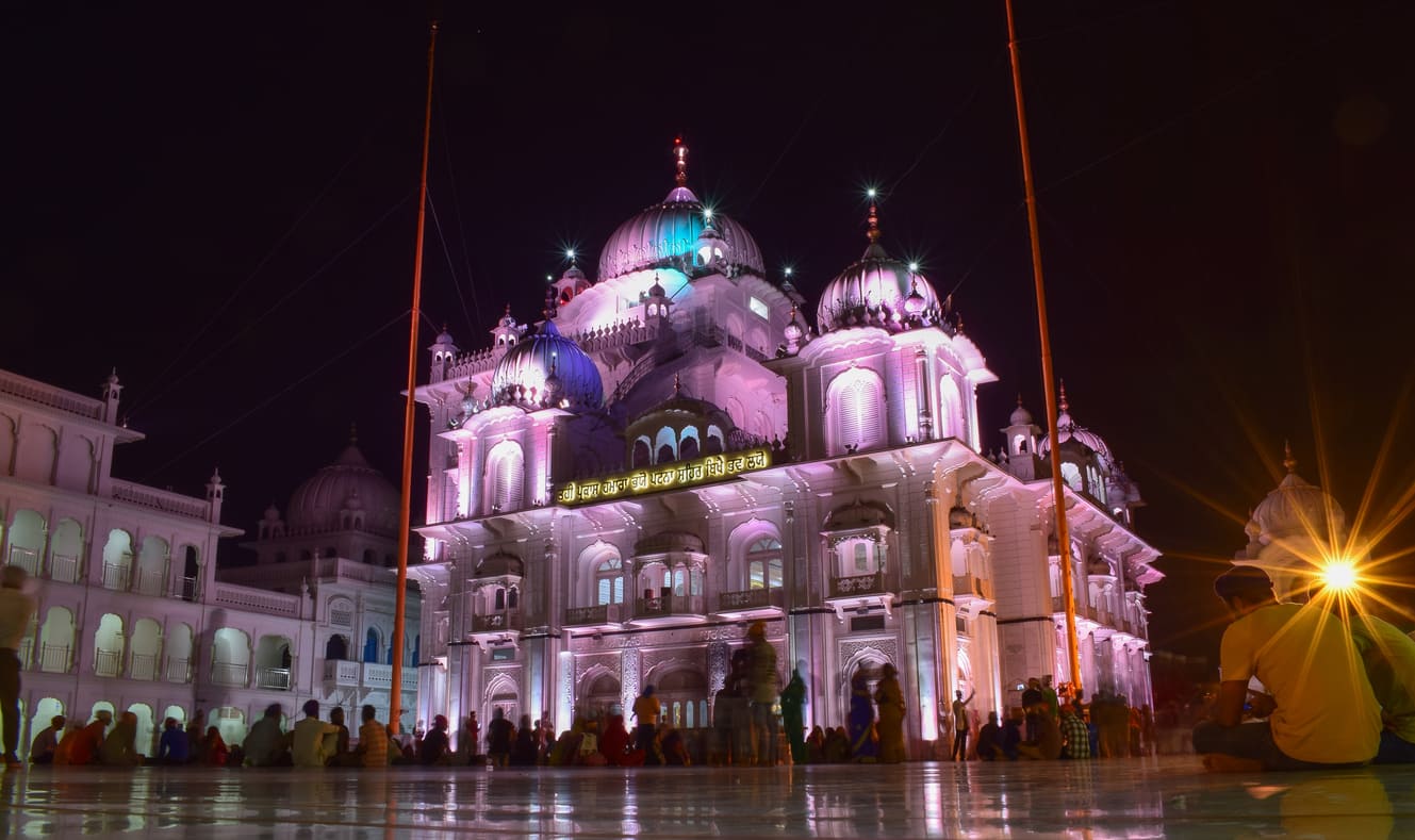 Takht Sri Patna Sahib, brightly lit at night, with devotees gathered in its serene and spiritual ambiance.