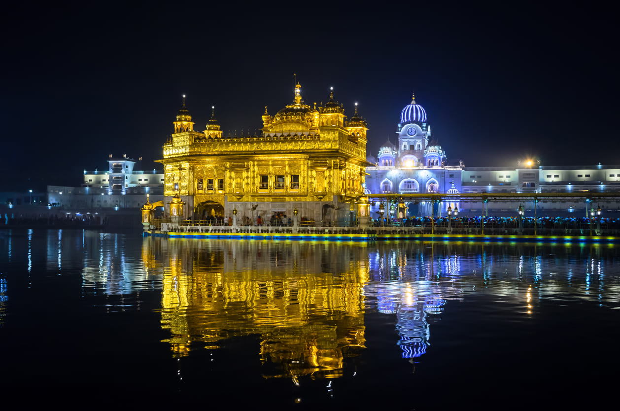 Golden Temple in Amritsar, magnificently lit at night, reflecting its golden glow in the surrounding water.