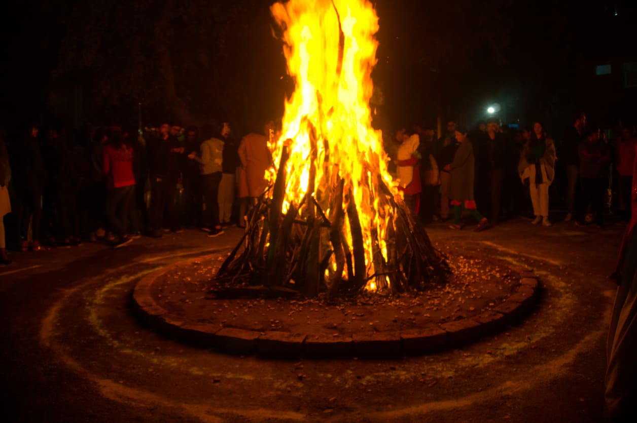 A vibrant bonfire burns brightly, surrounded by people joyfully celebrating the traditional harvest festival of Lohri.