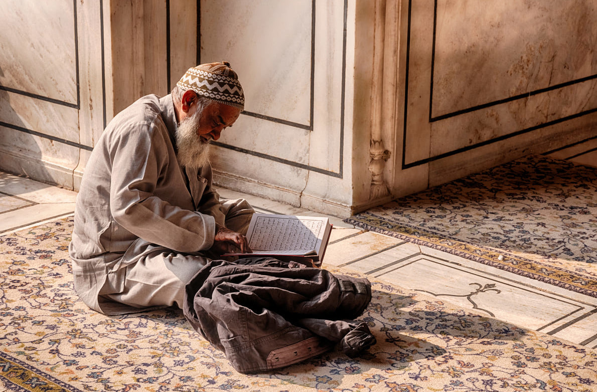 Elderly man deeply immersed in reading a holy book, symbolizing devotion and spirituality.