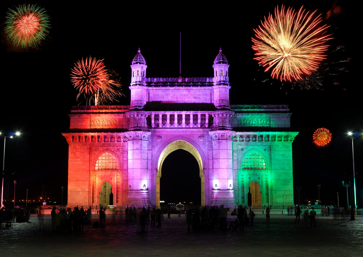 The Gateway of India in Mumbai is illuminated with colorful lights and surrounded by vibrant fireworks, celebrating the joy of New Year's Day.