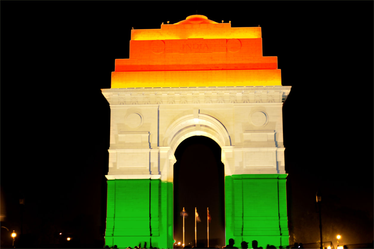 India Gate illuminated in vibrant saffron, white, and green lights, symbolizing the Indian national flag.