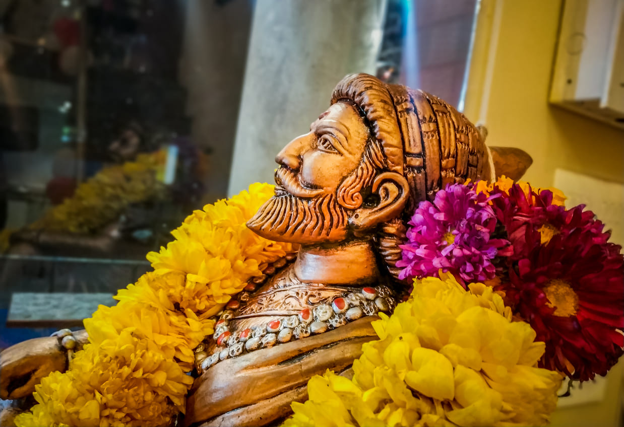 Beautifully decorated statue of Chhatrapati Shivaji Maharaj, adorned with vibrant flowers, honoring his legacy.