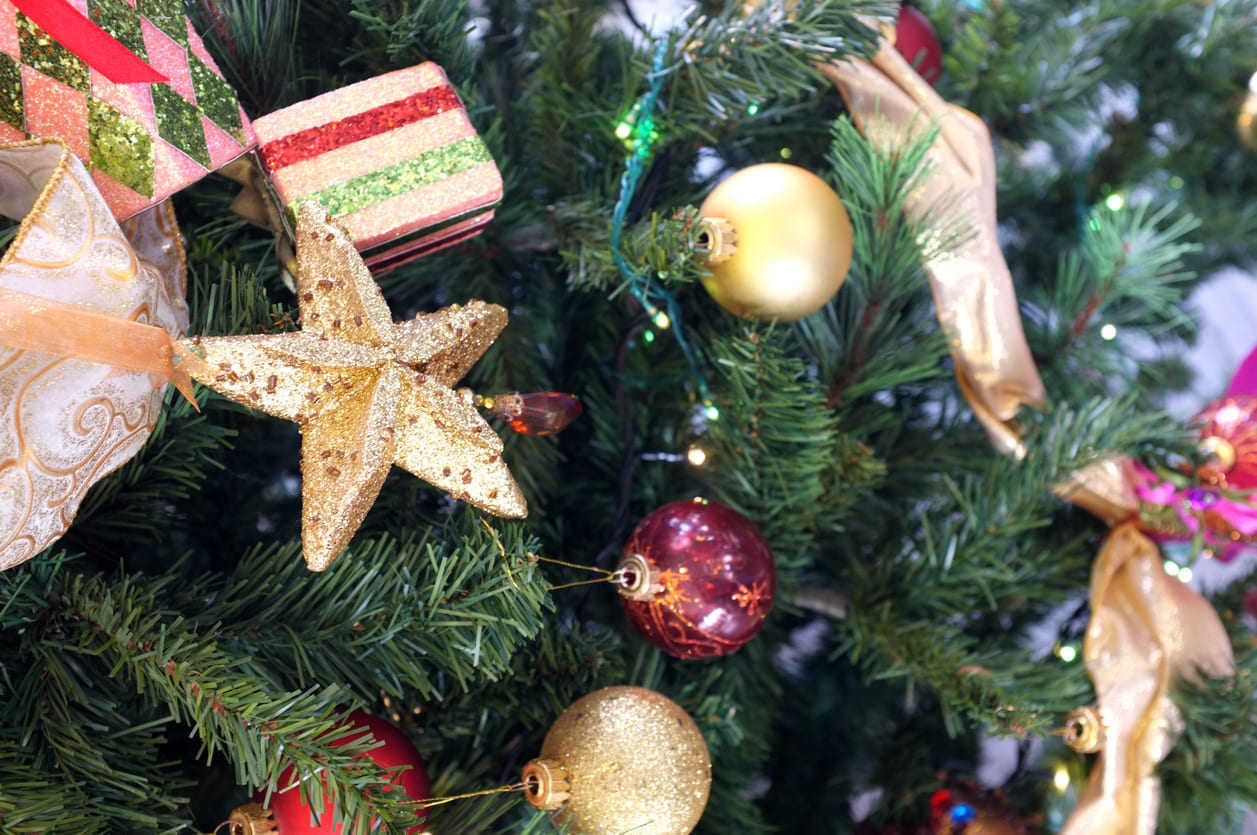 A close-up of a Christmas tree decorated with golden star and colorful ornaments, capturing the festive warmth of the holiday season.