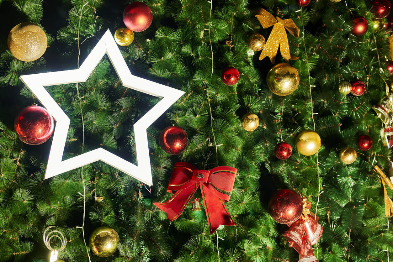 A close-up view of a Christmas tree adorned with red, gold ornaments, and a glowing star, capturing the festive warmth of Christmas Day in Indonesia.