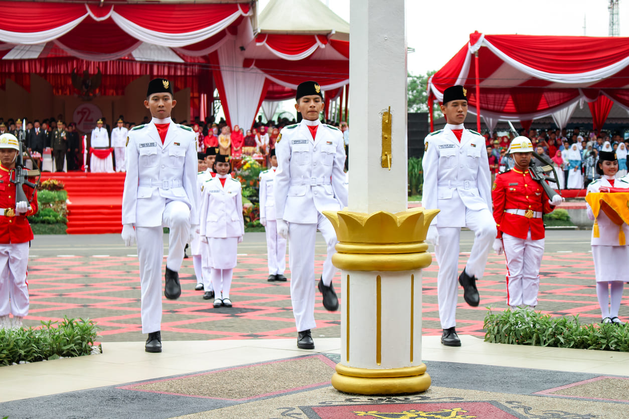 Flag raisers in crisp white uniforms perform the ceremonial hoisting of the Indonesian flag during Independence Day celebrations in Banjarmasin.