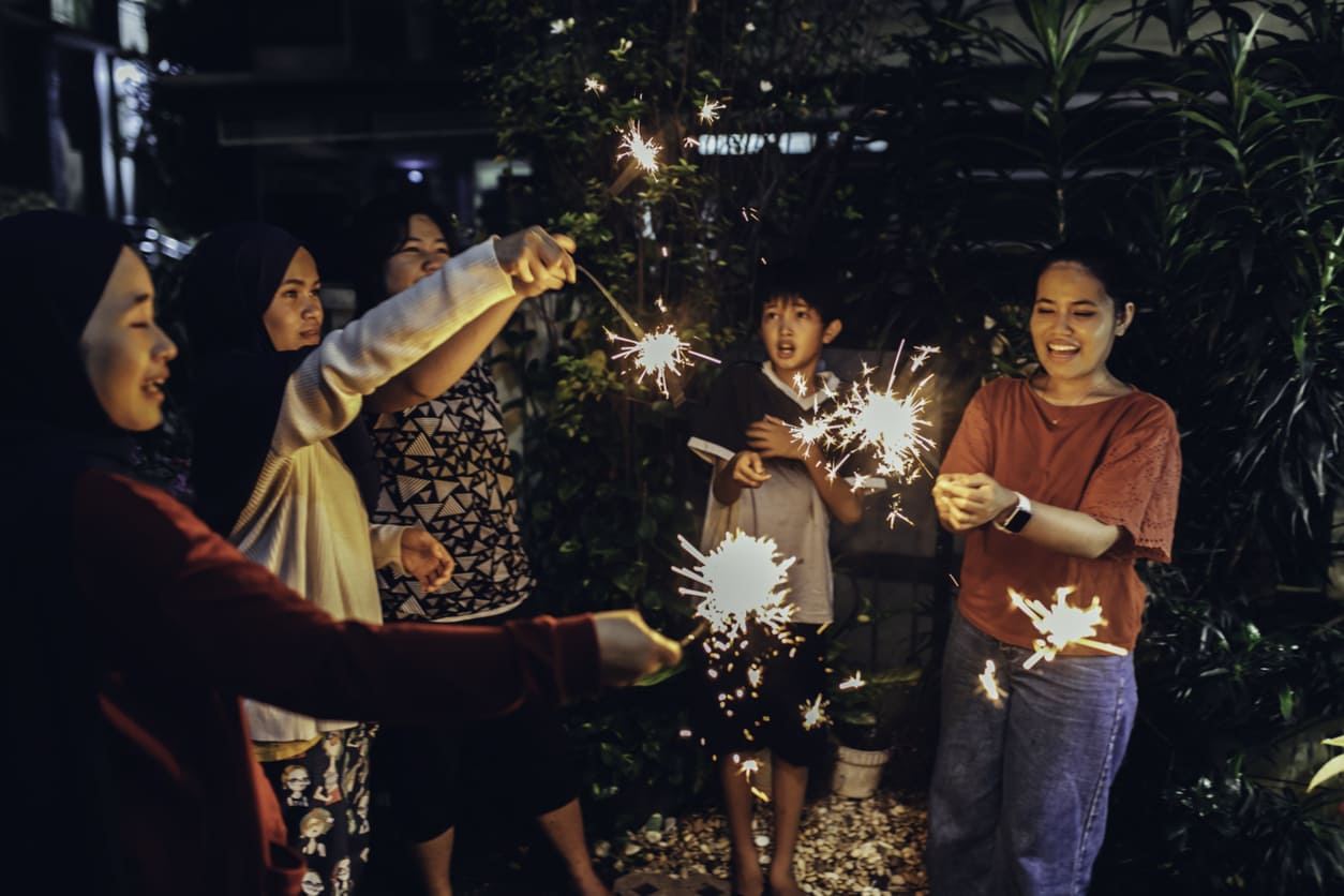A group of people happily holding sparklers at night, celebrating New Year's Eve with warmth and togetherness.