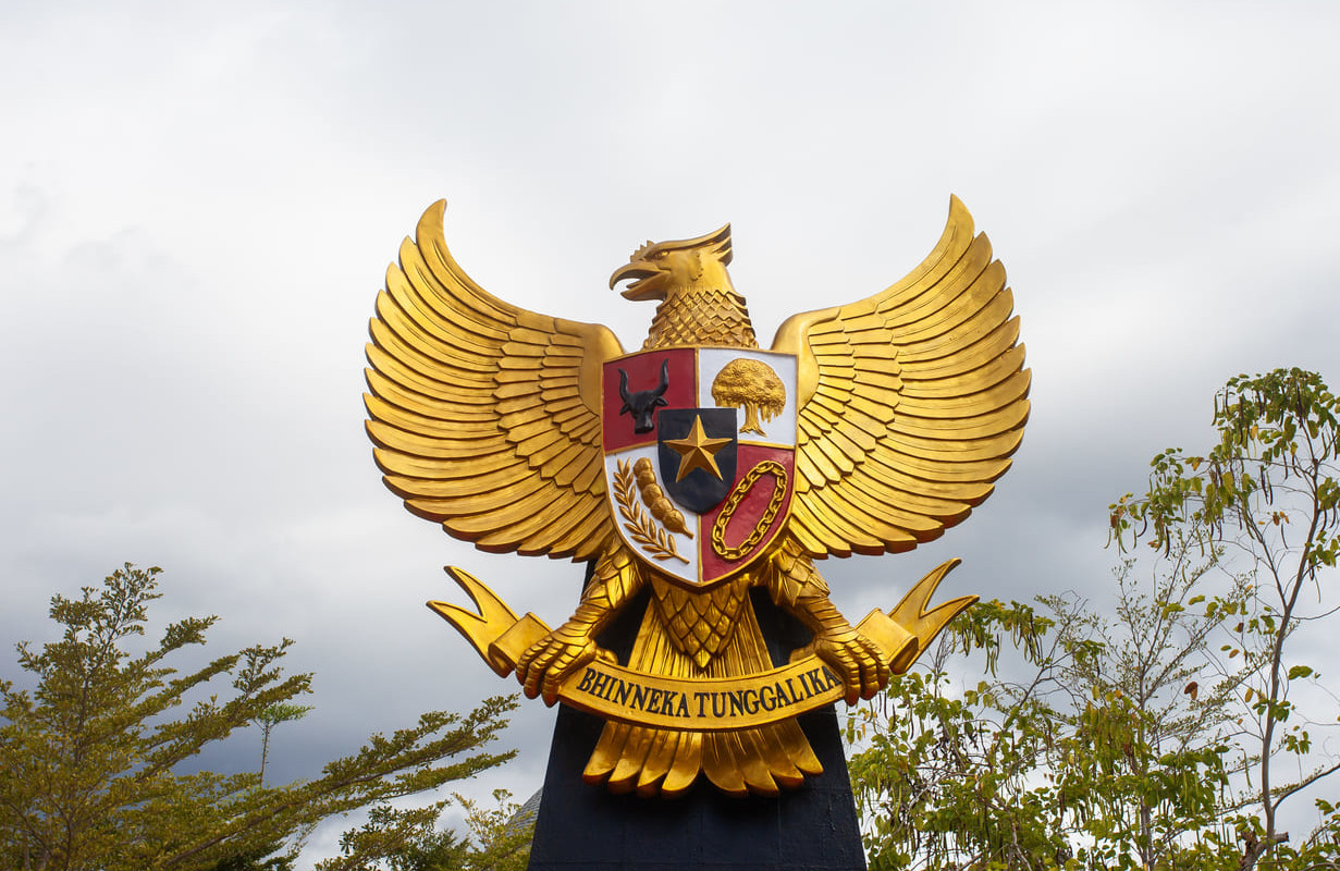 A golden statue of the Garuda Pancasila, Indonesia's national emblem, featuring symbols of the five foundational principles and the national motto.