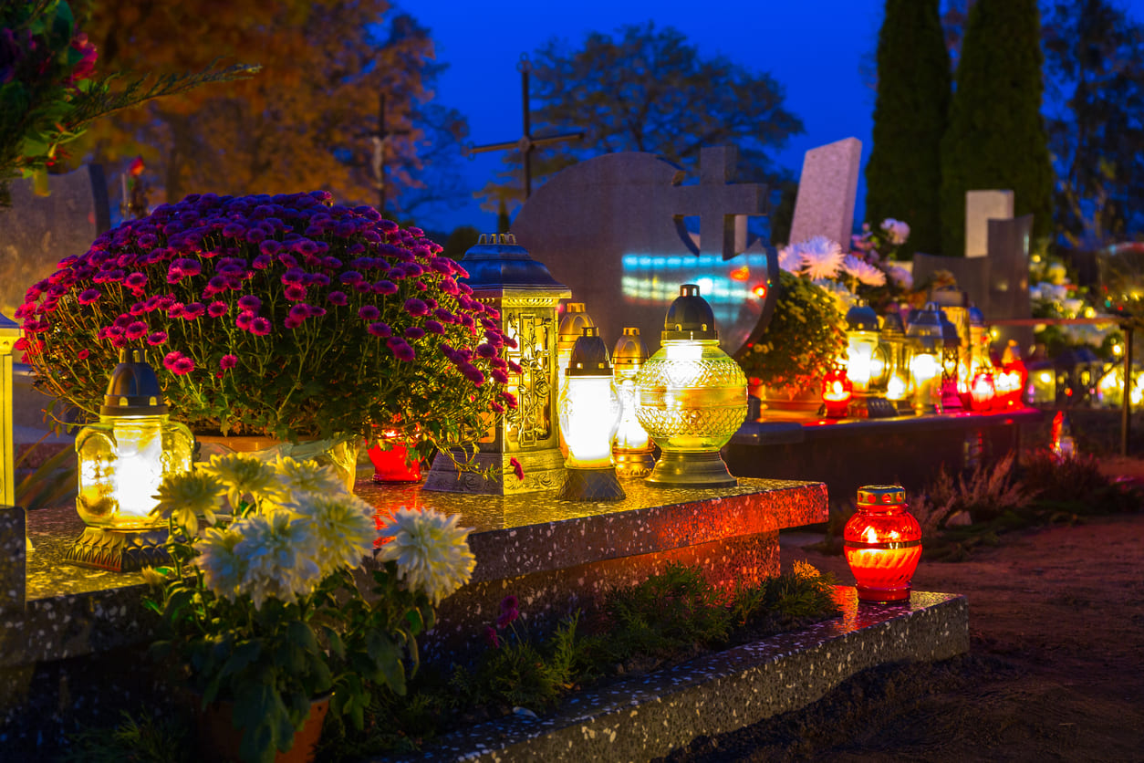 A cemetery lit by candles and adorned with flowers, capturing the solemnity of All Saints' Day.