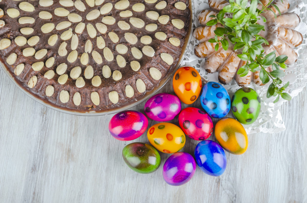 Colorful Easter eggs, a chocolate almond tart, and traditional baked goods, symbolizing the joy and celebration of Easter.