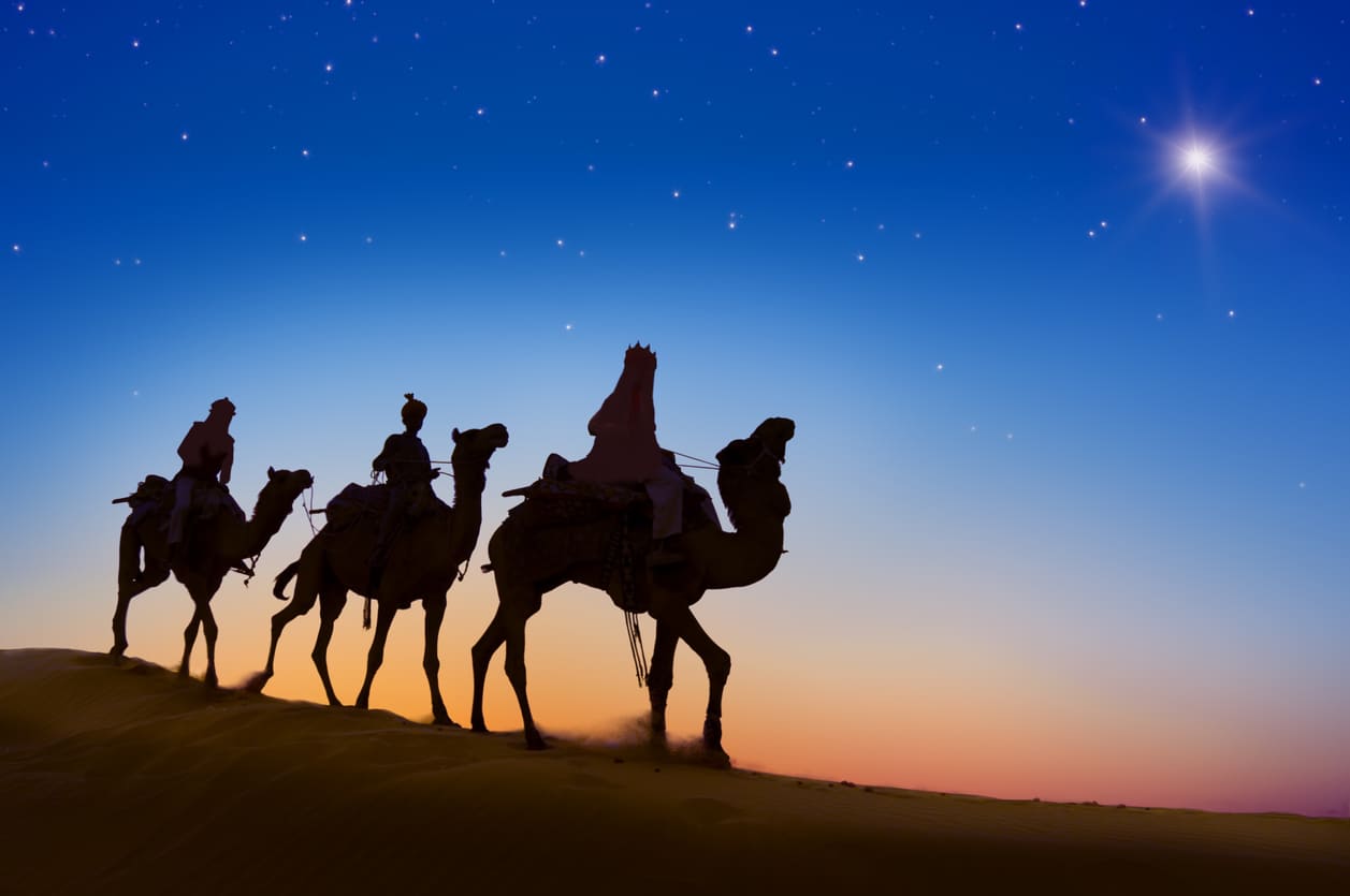 A silhouette of the Three Wise Men on camels traveling under a starry sky, guided by the Star of Bethlehem.