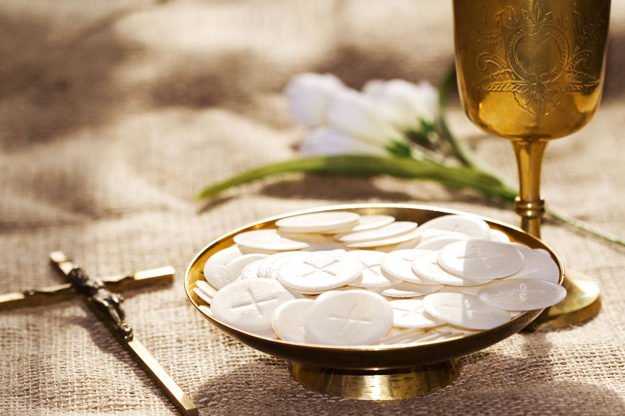 A golden chalice, Communion wafers, and a cross, symbolizing faith and the sacred rituals of Pentecost.