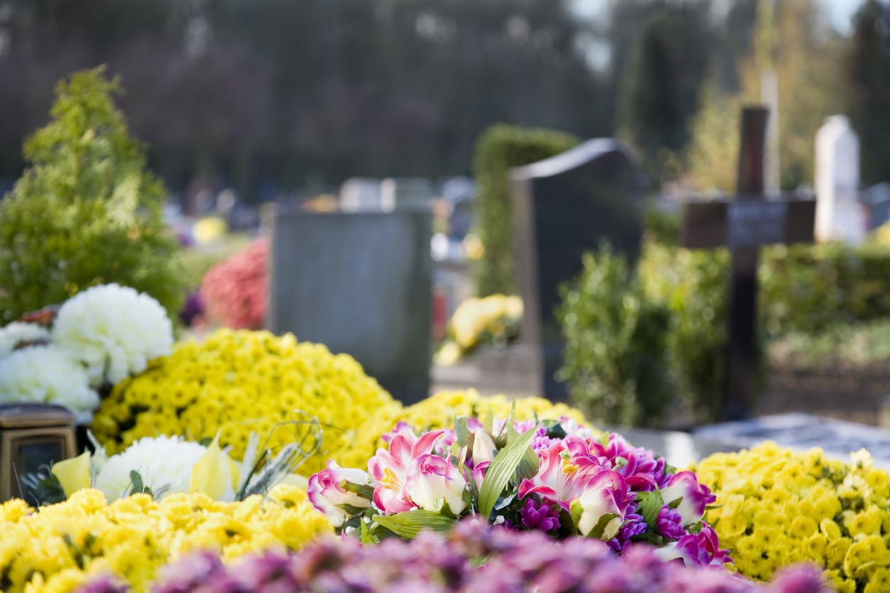 A cemetery scene with graves beautifully decorated with colorful flowers, symbolizing remembrance on All Saints' Day.