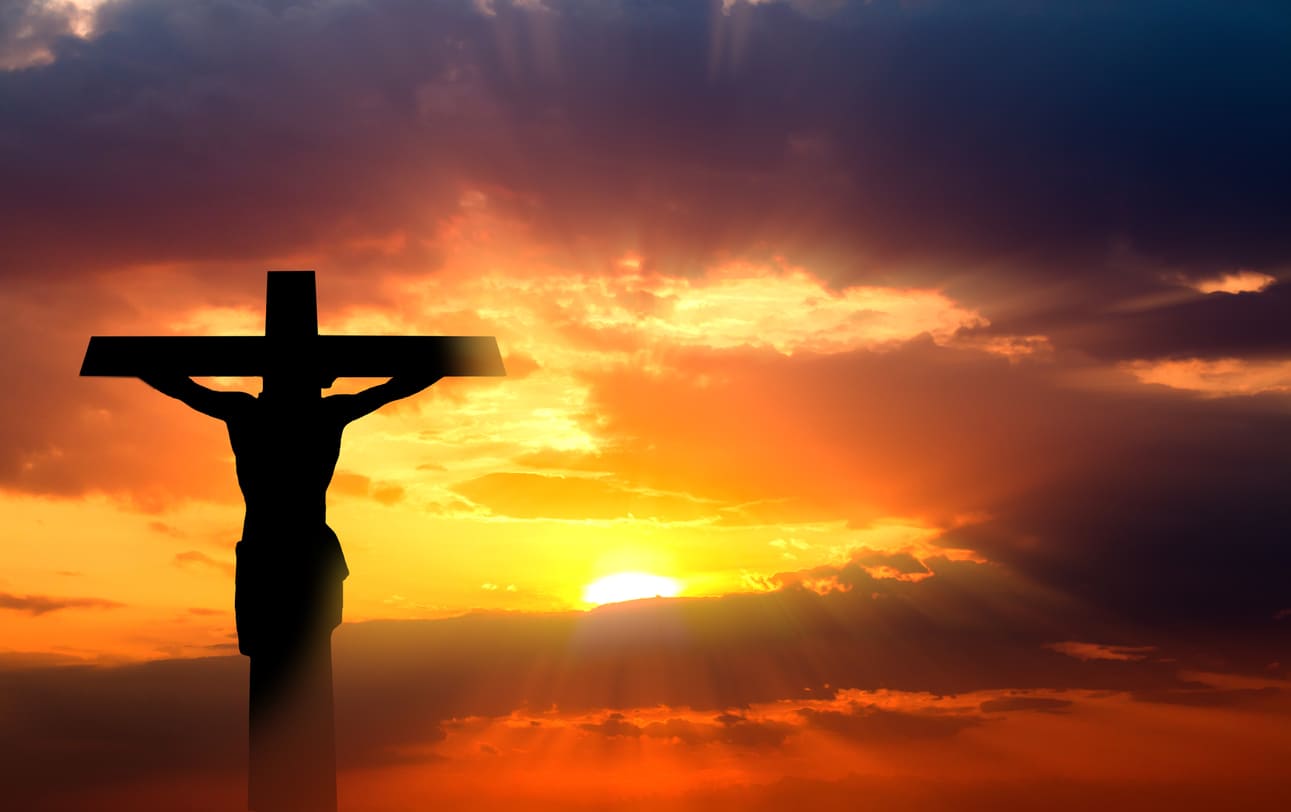 A silhouette of Jesus on the cross set against a vibrant sunset, symbolizing the solemnity of Good Friday.