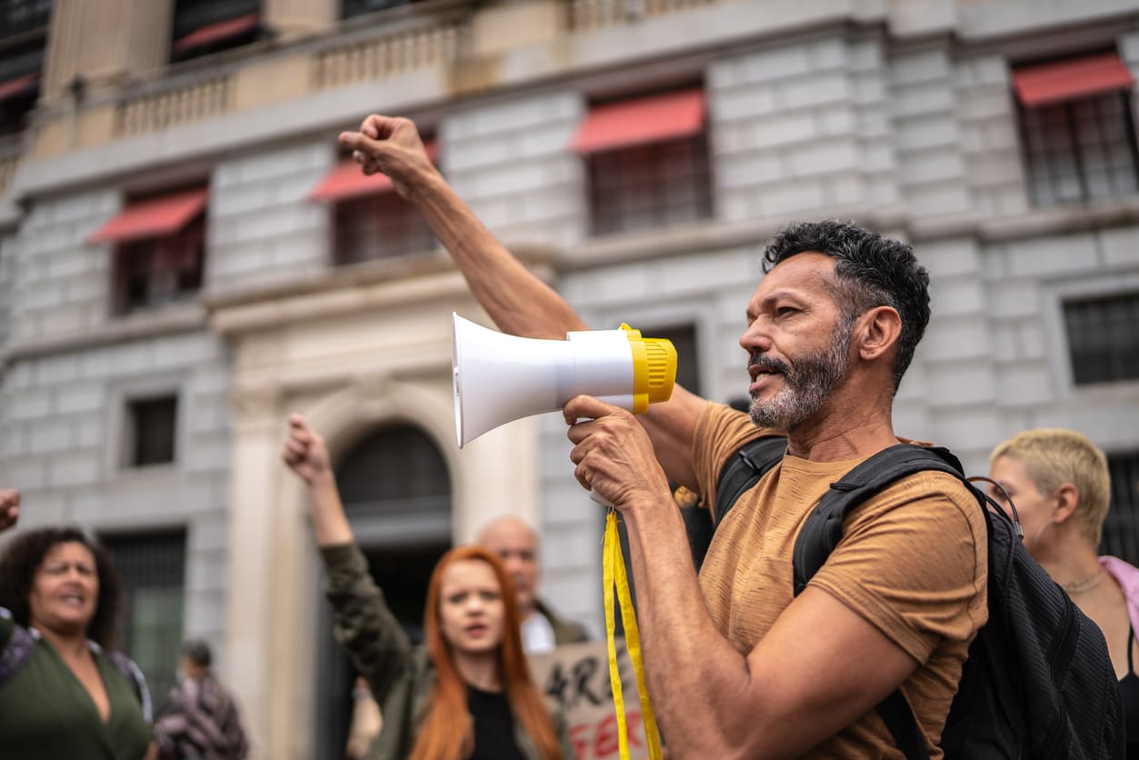 A passionate protester speaking through a megaphone during a May Day demonstration, advocating for workers' rights.